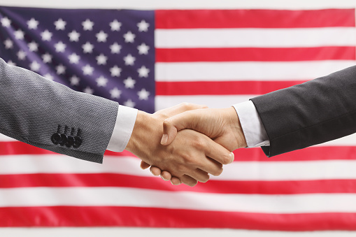Businessmen shaking hands in front of a USA flag