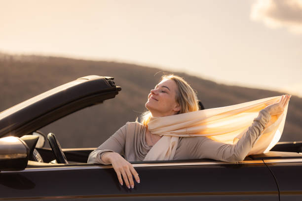 istock Woman whit her eyes closed sitting in convertible 2150655862