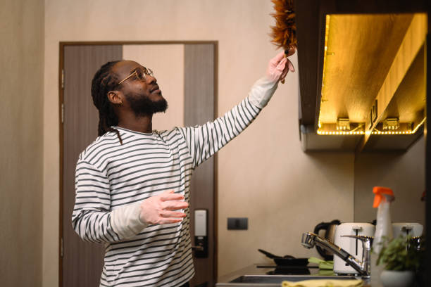 Mid adult men cleaning his apartment with a duster