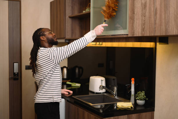 istock Happy bearded African man dusting shelf with a feather duster at modern kitchen 2150656197