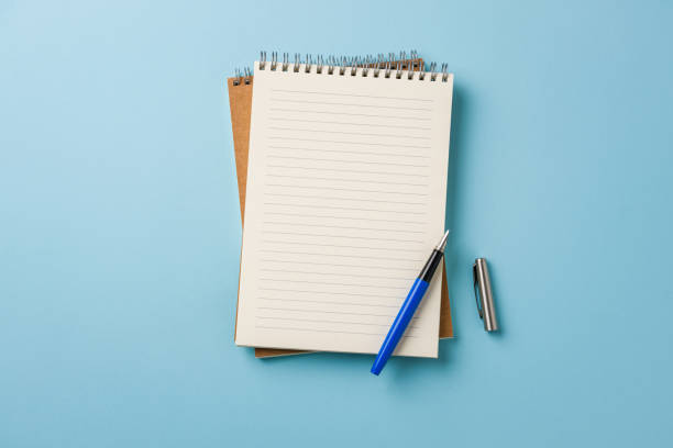 istock Top view of notebook and fountain pen on blue background 2150657435
