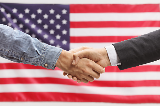 Casual man shaking hands with a politician in front of a USA flag