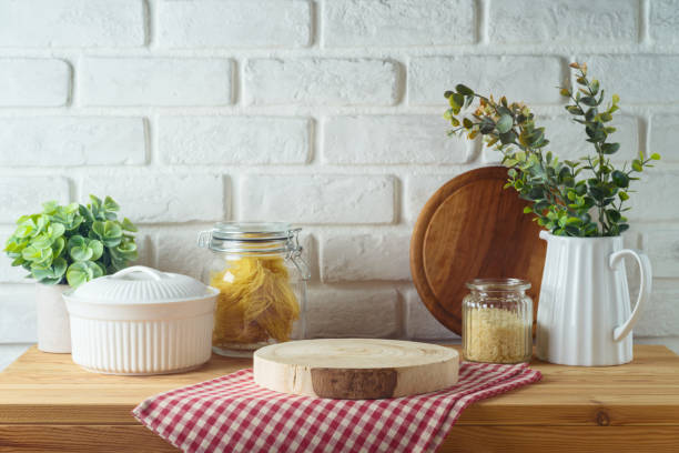 istock Empty wooden log  on kitchen table with food jars and plants over white brick wall  background.  Kitchen mock up for design and product display. 2150660032