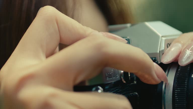 close up of female hand with long nails pressing the shutter button on old vintage retro camera film