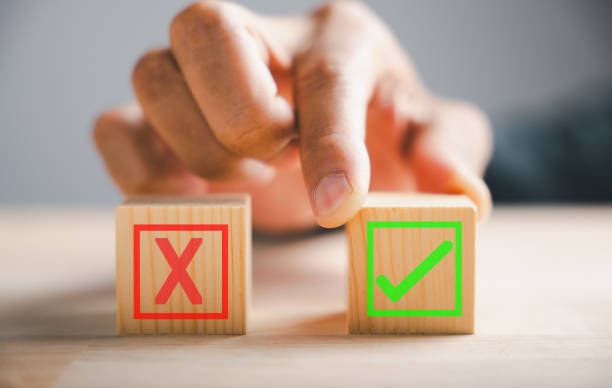 istock Between two wooden cubes businessman finger indicates check marks for right and wrong. Communicates choice and validation in decision-making. Think With Yes Or No Choice. 2150661055