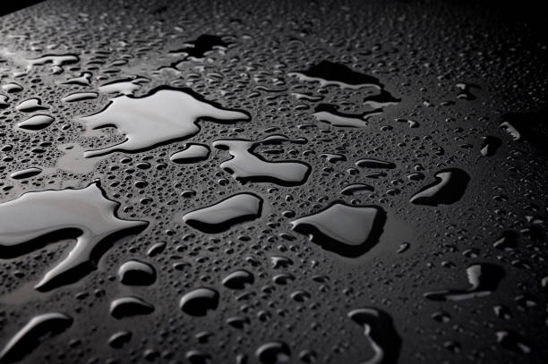 Stainless metal kitchen sink macro close up shot with big water droplets and scratched surface texture.