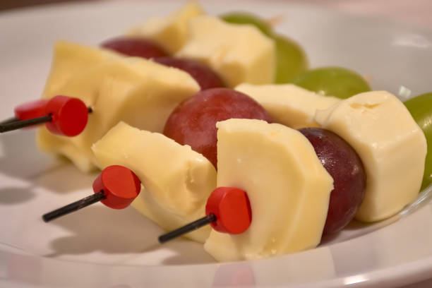 Skewer with cheese, green uba and black grapes and its toothpick with the red end