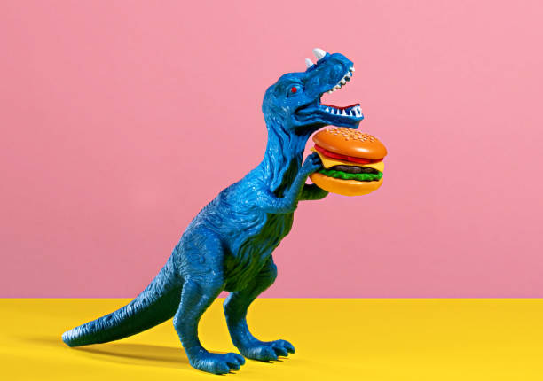 istock Happy blue dinosaur holding burger on pink and yellow background. 2150663839
