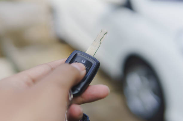 Hand holding key and pressing unlock button to open car doors