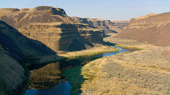 Aerial view of Palouse River flowing amidst Canyon against sky in Washington on a sunny day, USA.