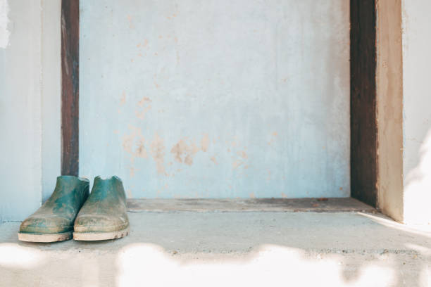 Old farming rubber boots in front of the door, selective focus