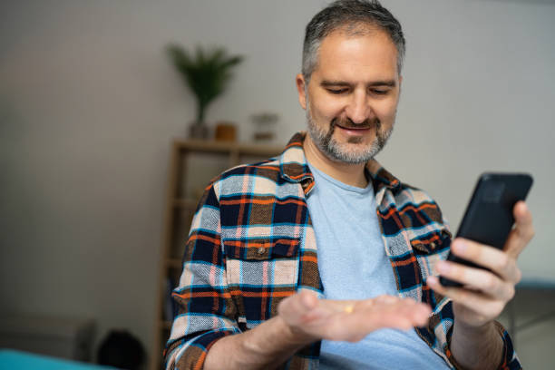 istock Man reading a medicine prescription on his smart phone while holding a pill 2150667422