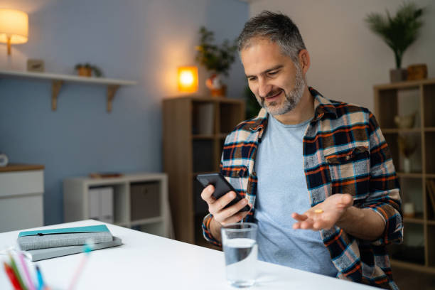 istock Man reading a medicine prescription on his smart phone while holding a pill 2150667427