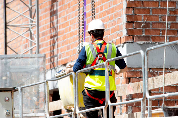 istock A worker in protective and safety equipment directs the lifting of a container with a concrete mixture on a crane chain at the height of a building under construction 2150668878