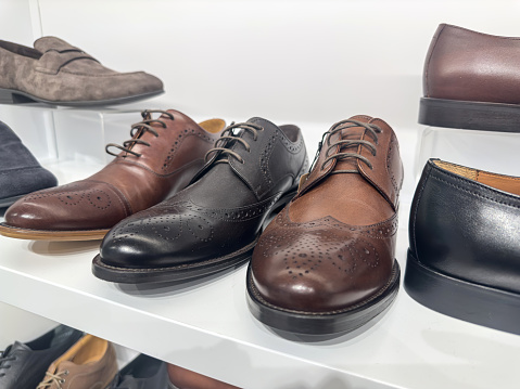 Stylish leather men's shoes on the shelf in the store in boutique. Male fashion style