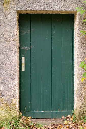 Green wooden door in a stone wall of an old farmhouse.
