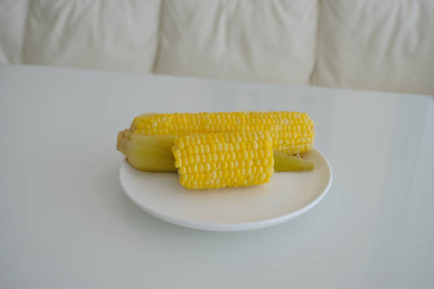 yellow corn on a white plate. boiled yellow corn on white plate and white table