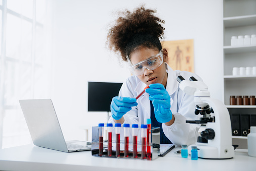 African Young scientists conducting research investigations in a medical laboratory, a researcher in the foreground is using a microscope in the medical industry