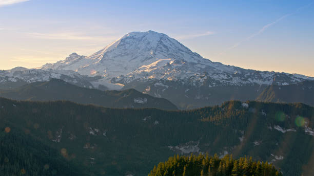 Aerial view of snowcapped Mount Rainier with forest in foreground against sky, Tacoma, Washington State, USA.