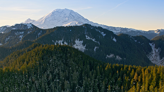 Aerial view of snow covered Mount Rainier with forest in foreground, Tacoma, Washington State, USA.