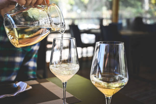 istock White wine pouring into glasses in a restaurant. 2150672659