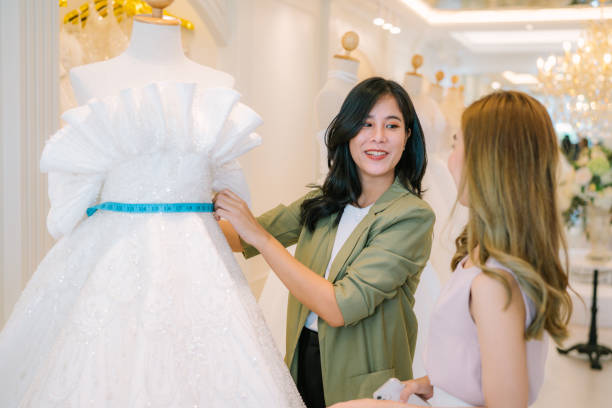 istock Asian bride is smiling while choosing wedding dress in modern wedding salon. 2150673847