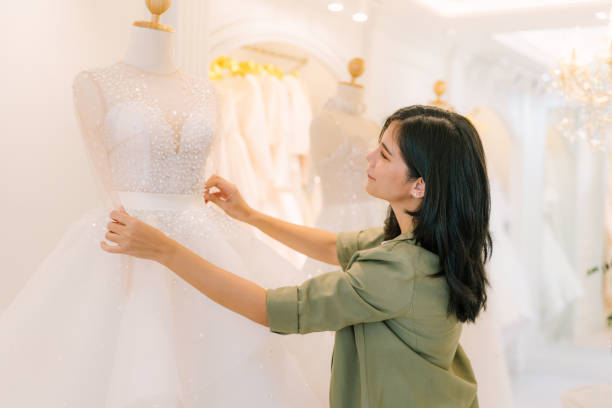 istock Attractive young bride is smiling while choosing wedding dress. 2150673848