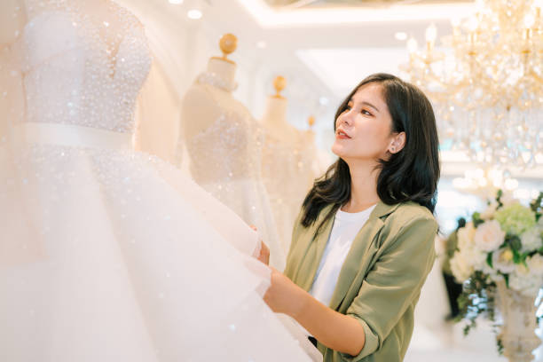 istock Attractive young bride is smiling while choosing wedding dress. 2150673849