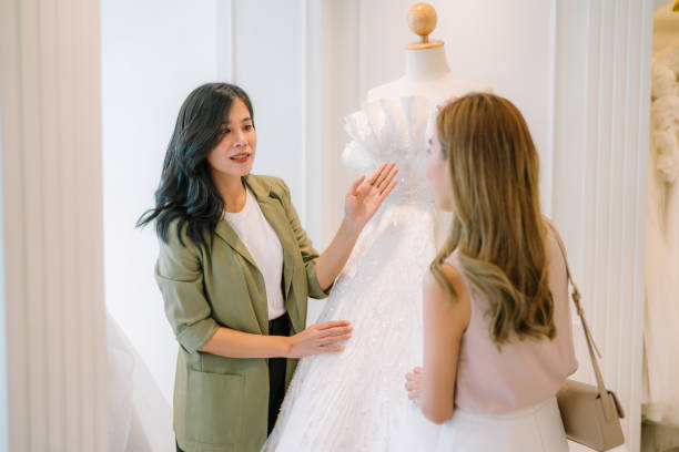 istock Asian bride is smiling while choosing wedding dress in modern wedding salon. 2150673895