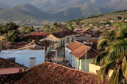 An aerial view looking down over the quaint houses and red tiled rood tops of streets in Trinidad, with mountains in the background. Trinidad has been declared a UNESCO world heritage site