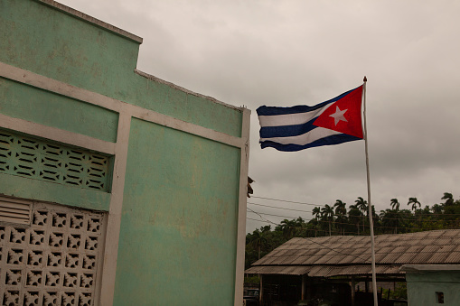 A Cuban flag flying next to a building on the outskirts of the city of Barocoa.