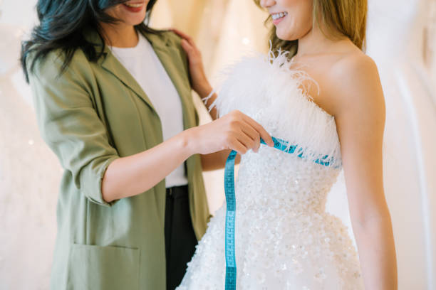 istock Asian bride is smiling while choosing wedding dress in modern wedding salon. 2150674787