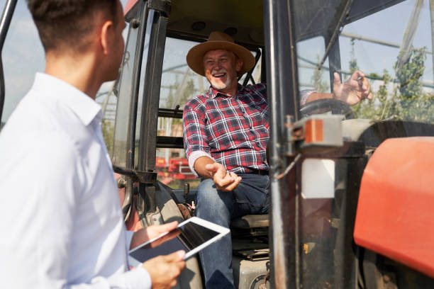 istock Senior farmer and sales representative next to tractor talking over digital tablet 2150676039