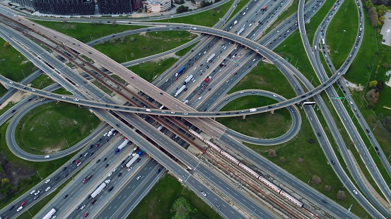 Metropolitan arteries pulsing with cars, aerial showcase of urban pace. Transportation web: Aerial view of a sprawling highway network with seamless vehicular motion. Motorway concept