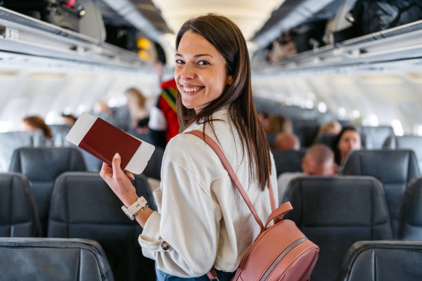 Young Woman Boarding An Airplane Portrait of a beautiful young woman boarding an airplane in Austria. Finding her seat. around the world stock pictures, royalty-free photos & images