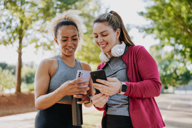 Two fitness friends smiling using smartphone
