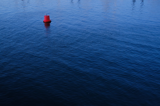 A red buoy isolated floating on the blue water. La Turballe, France - April 28, 2024.