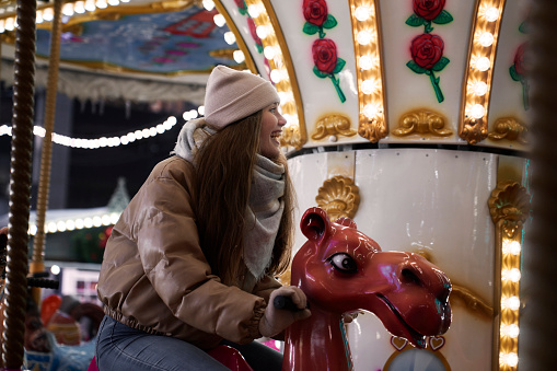 Young caucasian woman having fun on the carousel