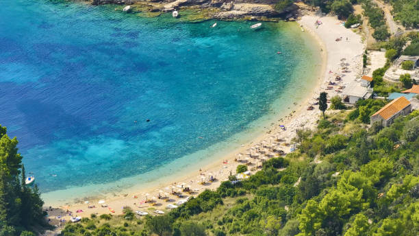 istock AERIAL: Flying above a sandy beach with recliners facing the turquoise sea. 2150681783