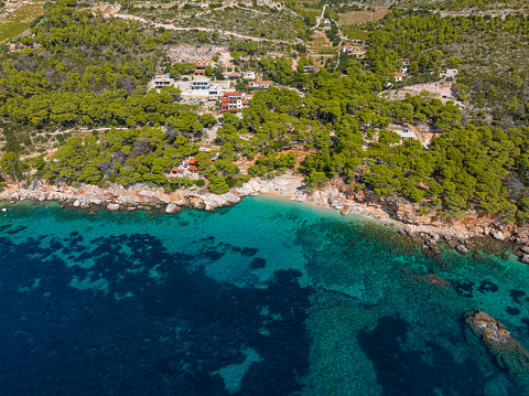 AERIAL: Small sandy beach of remote luxury seafront houses is hidden under the fragrant pine trees. Scenic drone view of a small beach underneath the beachfront houses facing turquoise Adriatic sea.