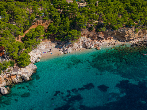 AERIAL: Scenic drone shot of a hidden gem of a sandy beach in a remote part of a Mediterranean island. Flying above a secluded bay on the island of Hvar with tourists enjoying the summer sunshine.