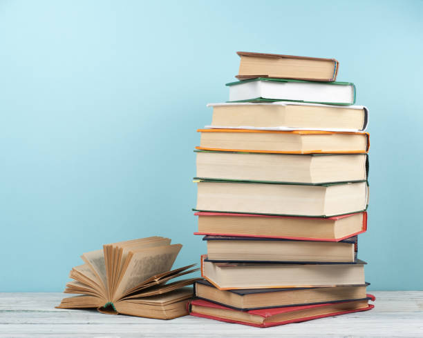 istock Open stacking book, hardback colorful books on wooden table and blue background. Back to school. Copy space for text. Education business concept. 2150682152