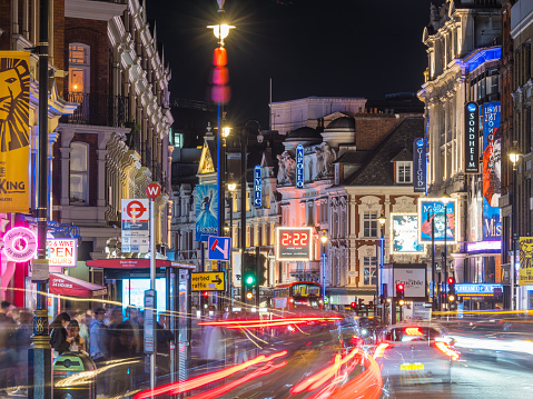 Traffic zooming along Shaftesbury Avenue past the tourist crowds and the billboards of London’s vibrant theatre district at night.