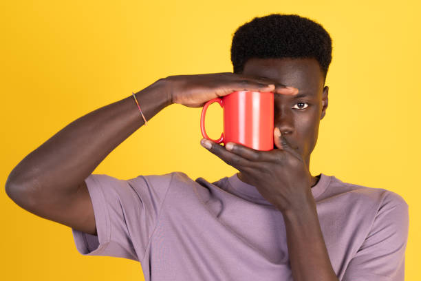 A man with a red mug in his hand is looking at the camera
