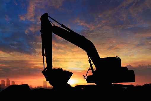 Crawler excavators silhouette are digging the soil in the construction site. on  sunset background