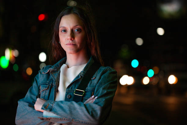 side view of thoughtful woman looking at city lights at night in dark