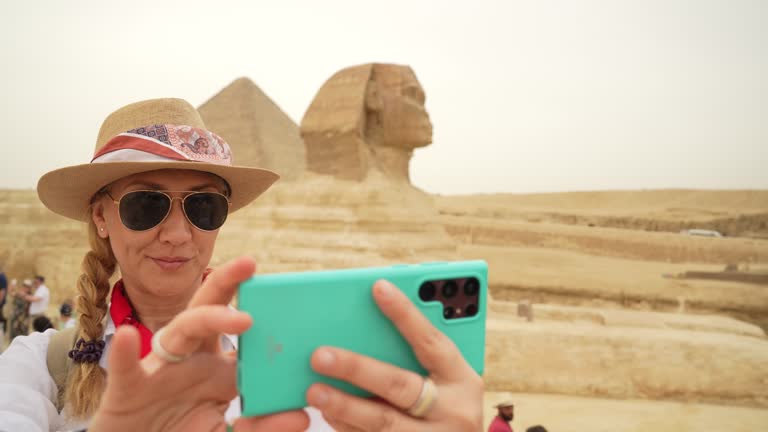 4K Video of Woman standing in front of the background of Sphinx and taking selfie with smartphone. Giza, Cairo, Egypt