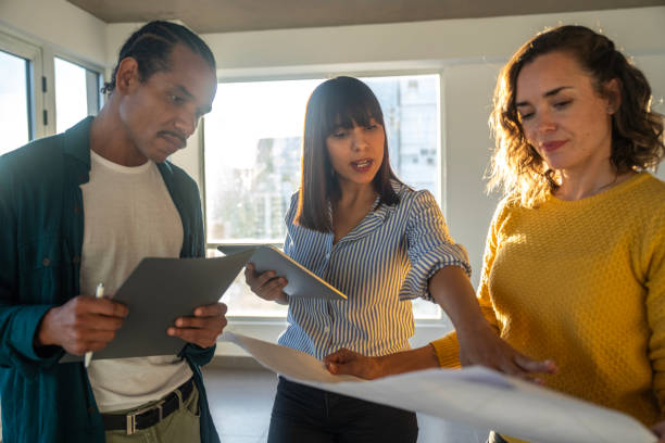 istock Front view of female interior decorator explaining renovation plans to diverse couple 2150687027