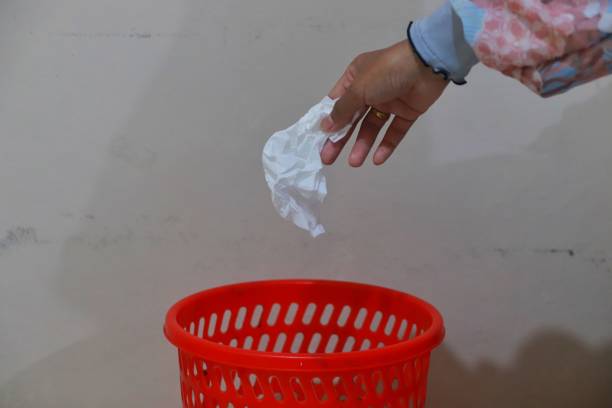 istock Hand throwing tissue waste in red wastebasket 2150687093