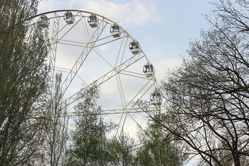 Ferris wheel in the spring in the park against the background of the sky with clouds